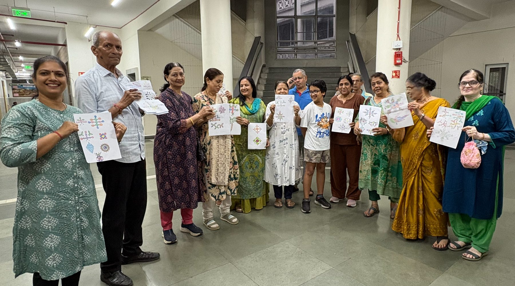 Participants standing together holding up their finished artwork at the close of a session.