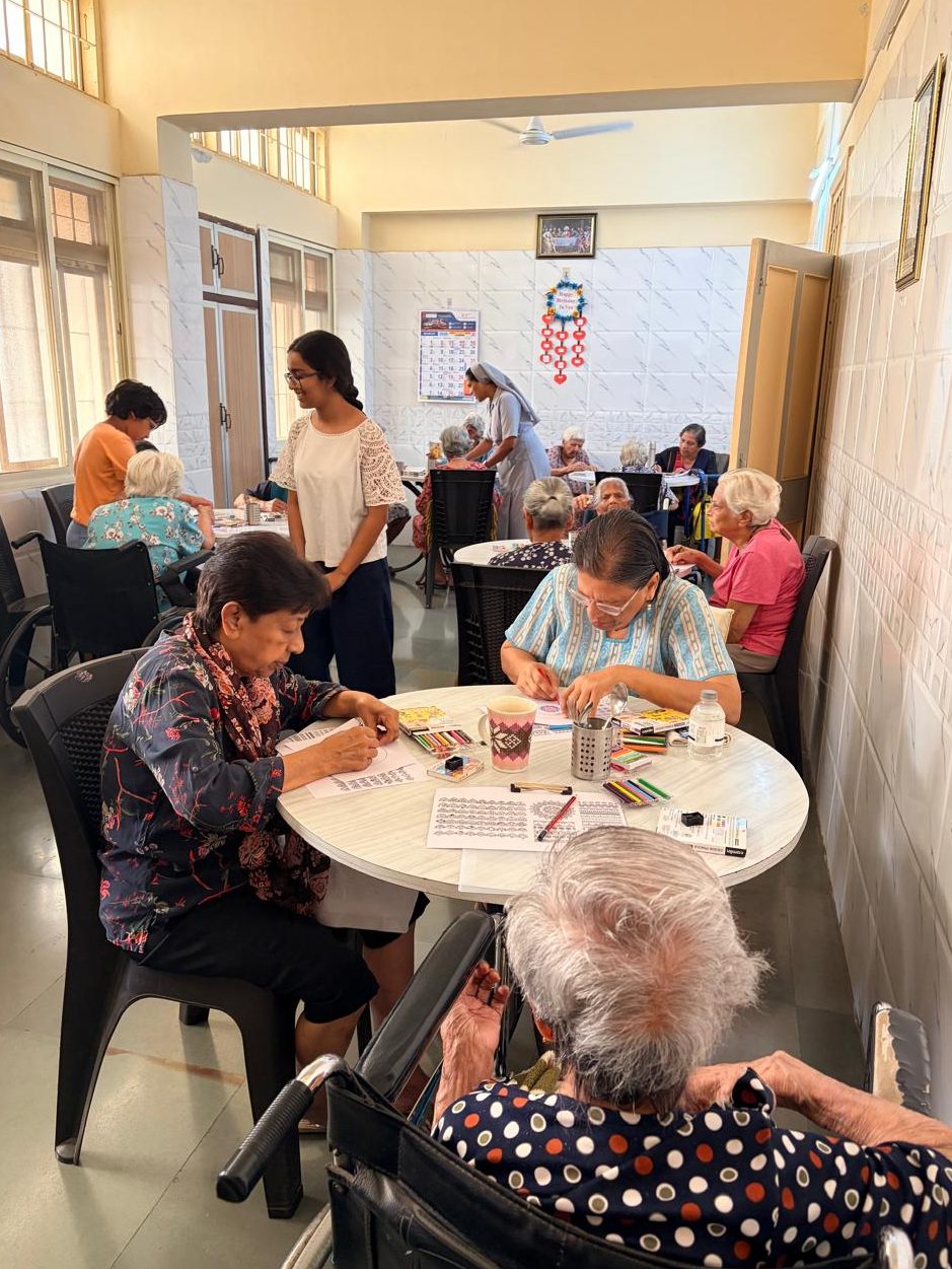 Residents of a care home seated around a table working on art activities.