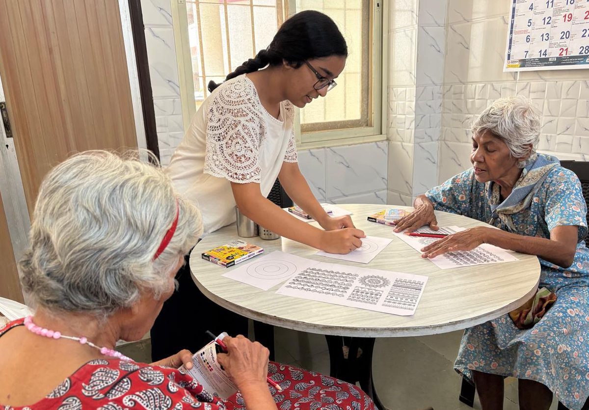 A bright room where older participants work on art at a round table.