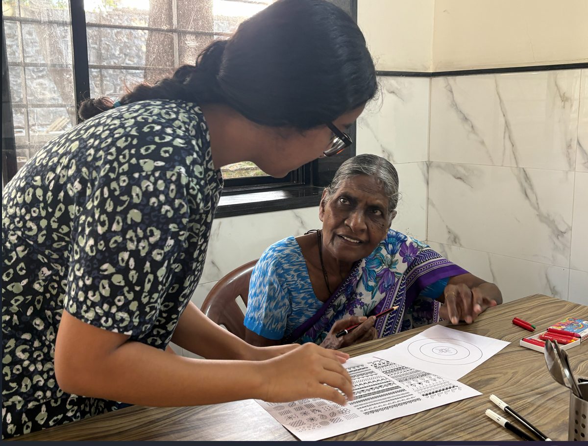 A facilitator guiding an older participant through a printed pattern worksheet.